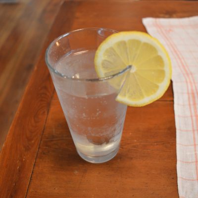 Glas mit kaltem Wasser und Zitronenscheibe am Rand